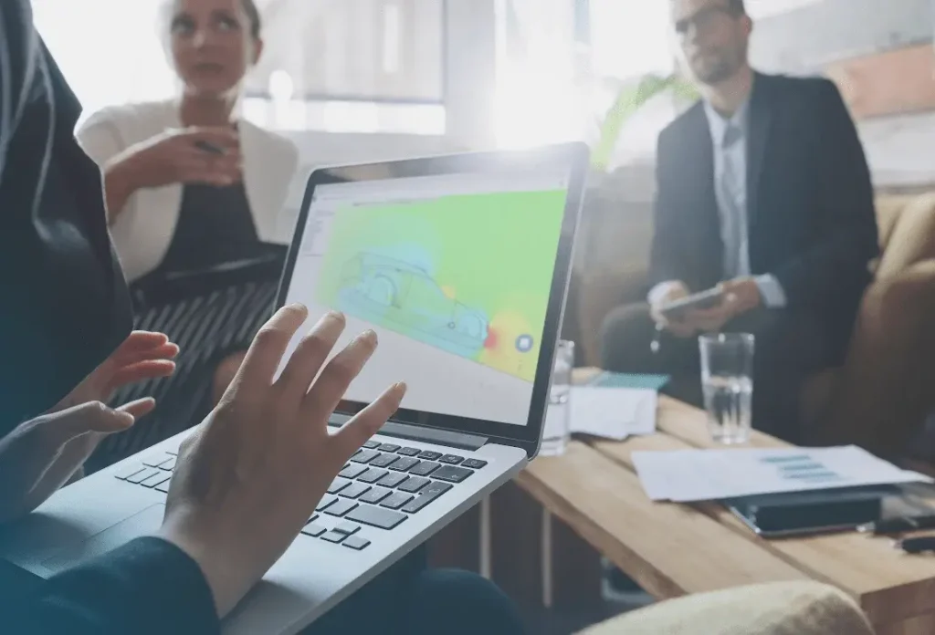 A discussion between three people with a SimScale automotive simulation image on a laptop in the foreground